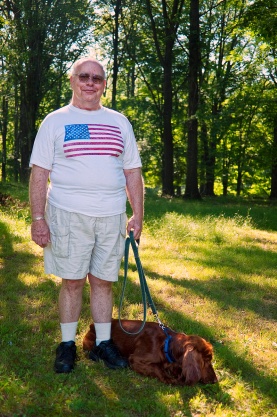 Image of man in American flag tee-shirt walking his Irish setter on the 4th of july