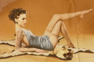 This is a distressed image of a pin up girl wearing blue lingerie lounging on a lion skin rug on a orange background.